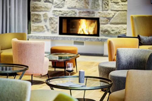 a living room with chairs and tables and a fireplace at Königswieser Hof in Königswiesen