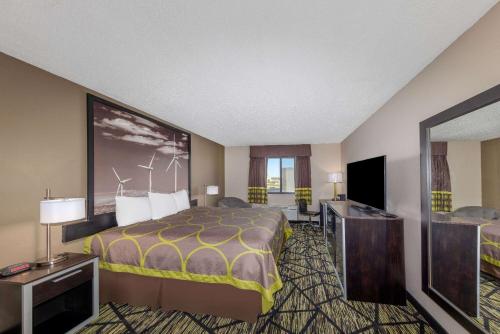 a hotel room with a bed and a flat screen tv at Super 8 by Wyndham Pratt in Pratt