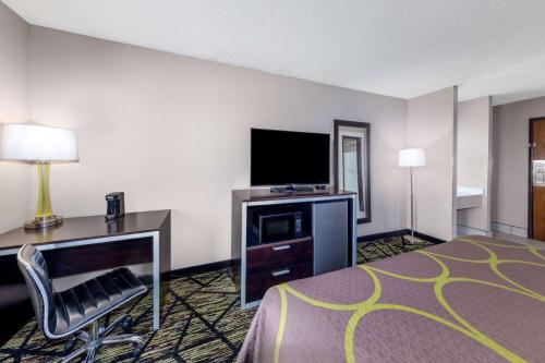 a hotel room with a bed and a desk and a television at Super 8 by Wyndham Pratt in Pratt