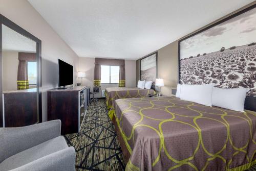 a hotel room with two beds and a flat screen tv at Super 8 by Wyndham Pratt in Pratt