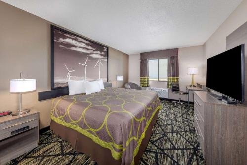 a hotel room with a bed and a flat screen tv at Super 8 by Wyndham Pratt in Pratt
