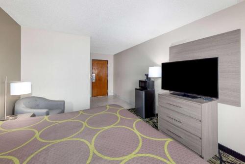 a hotel room with a bed and a flat screen tv at Super 8 by Wyndham Pratt in Pratt