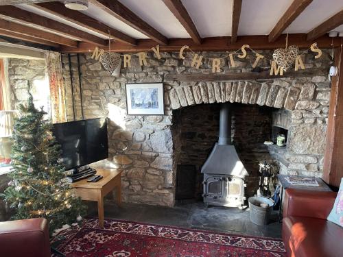 a living room with a stone fireplace with a christmas tree at Tunnel Cottages at Blaen-nant-y-Groes Farm in Aberdare