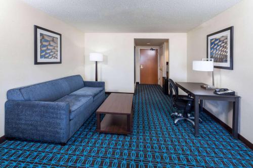 a living room with a blue couch and a desk at Wingate by Wyndham Chicago Schaumburg in Schaumburg