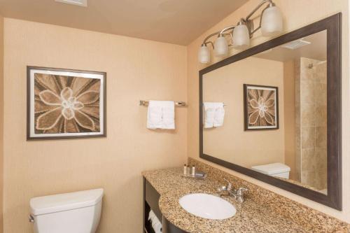 a bathroom with a toilet and a sink and a mirror at Wingate by Wyndham Houma in Houma