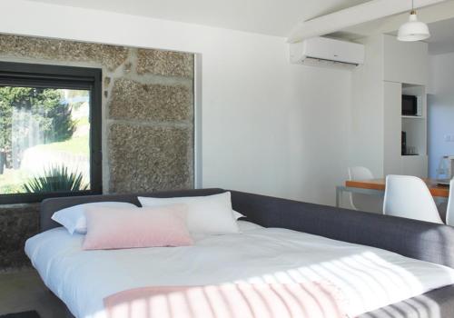 a bedroom with a white bed with a pink pillow at Quinta Milhão - Casa do Pomar in Guimarães