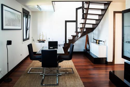 een kamer met een tafel en stoelen en een trap bij Apartamentos Redondela - A Casa da Praia in Redondela