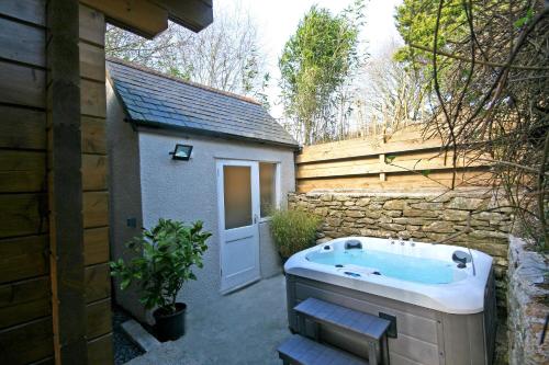 un patio trasero con jacuzzi junto a un edificio en Yealm Cabin Self Catering Log Cabin in Devon with Hot Tub en Plymouth