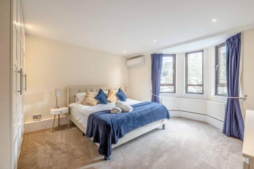 a bedroom with a bed with blue sheets and windows at Hidden Gem With Windsor Castle Views & Parking in Windsor