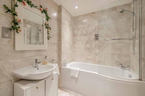 a bathroom with a white tub and a sink and a bath tubermott at Hidden Gem With Windsor Castle Views & Parking in Windsor