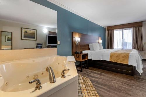 a hotel room with a bed and a bath tub at Quality Inn & Suites Ft Jackson Maingate in Columbia