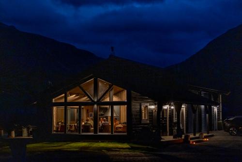 a house lit up at night with mountains in the background at Fjelleventyret gårdsovernatting in Skjåk