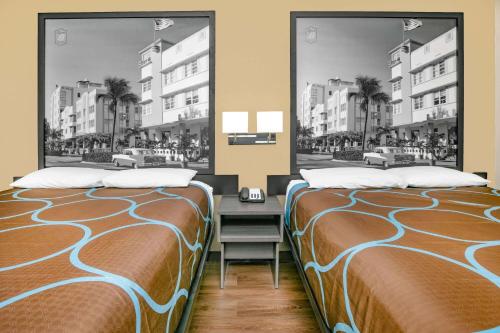 two beds sitting next to each other in a bedroom at Super 8 by Wyndham Moss Point in Moss Point