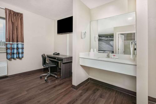 a bathroom with a sink and a desk and a mirror at Super 8 by Wyndham Moss Point in Moss Point