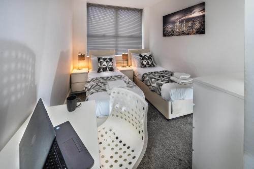 a bedroom with two beds and a desk with a chair at Modern & spacious 2-bed flat with secure parking in Reading