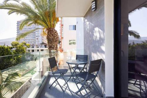 a balcony with chairs and a table and a palm tree at Sunnyland Lago Martianez 3 in Puerto de la Cruz