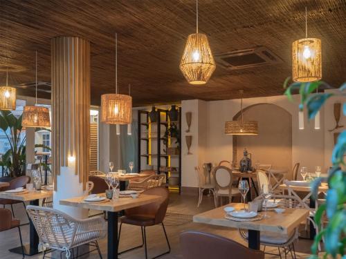 een restaurant met tafels en stoelen en kroonluchters bij Hotel Caribe in Rota