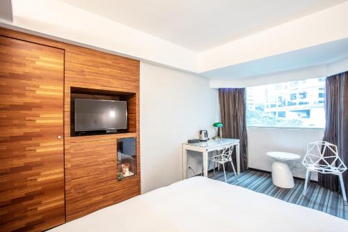 a hotel room with a bed and a flat screen tv at Hotel Cloud Riverside in Tamsui