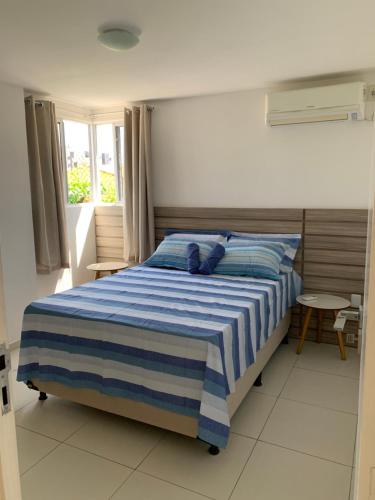 a bedroom with a blue and white bed with a window at Jóia Rara pertinho da Praia! in João Pessoa