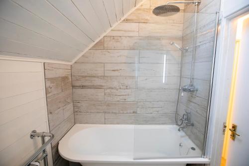 een badkamer met een wit bad en een douche bij Stunning lodge on the lake in South Cerney