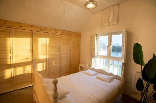 a bedroom with a white bed and a window at Stunning lodge on the lake in South Cerney