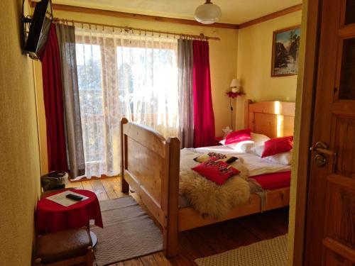 a bedroom with a bed with red pillows and a window at Durda in Poronin