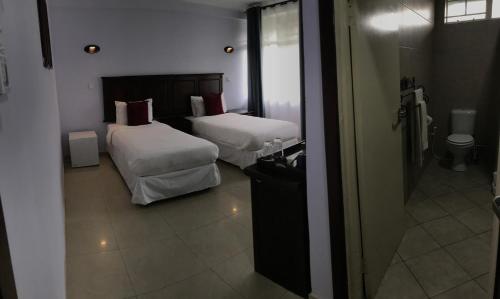 a hotel room with two beds and a mirror at Crescent Lodge in Livingstone