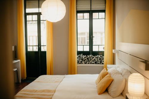 een slaapkamer met een bed en 2 ramen bij H.ö.H in Porto