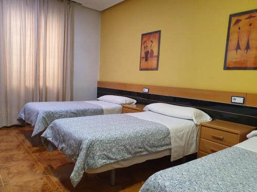 a room with three beds in a room at Hostal Zamorán in Madrid