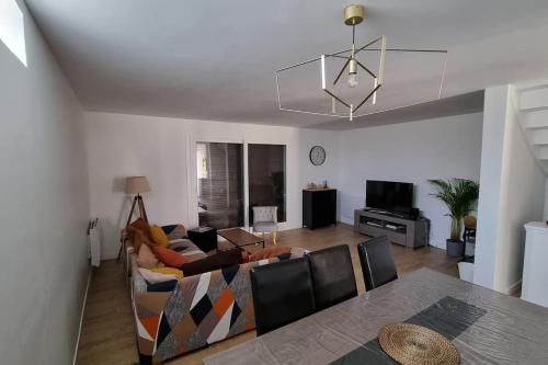 a living room with a couch and a table at Maison Chaleureuse in Villepinte