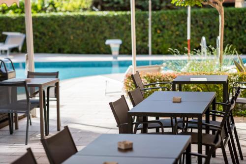 a patio with tables and chairs next to a pool at Hotel Imperial ***S in Garda