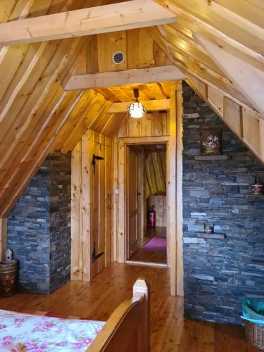 an attic with a stone wall and wooden beams at Durda in Poronin