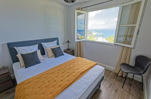 ein Schlafzimmer mit einem großen Bett mit einem großen Fenster in der Unterkunft L'Eden Blue à Saint Gilles les Bains, magnifique vue mer in Saint-Gilles-les-Bains