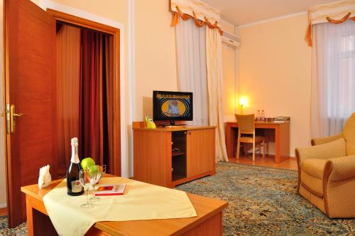 a living room with a tv and a couch and a table at Altyn Dala Hotel in Astana