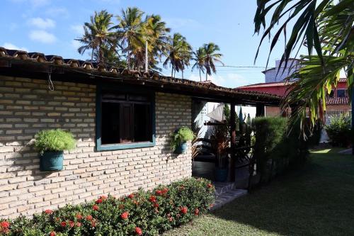 une maison en briques avec une fenêtre et des palmiers dans l'établissement Barra Adventure Pousada, à Mataraca