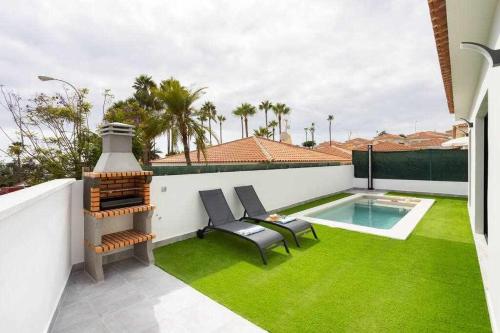 a patio with green grass and a swimming pool at Sunnyland Villa Sueño Azul in Callao Salvaje