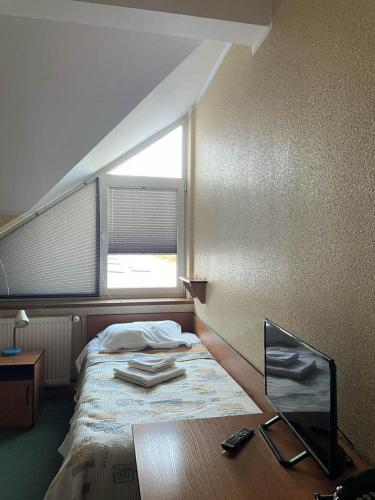 a bedroom with a bed with a window and a chair at Hotel SenS in Mierzyn