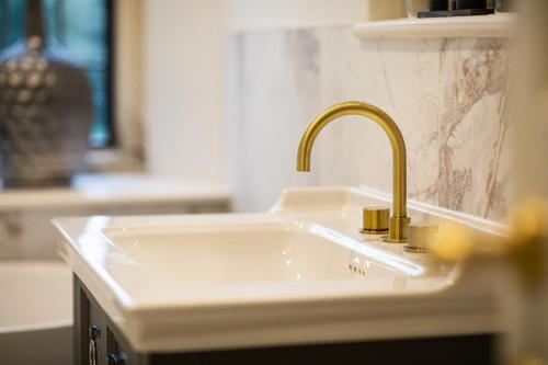 a white kitchen sink with a gold faucet at The Greenway Hotel & Spa in Cheltenham