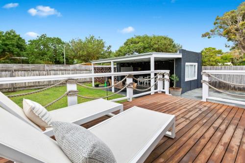 Una terraza con muebles blancos y un cenador. en Berkeley Beach House Safety Beach, en Safety Beach