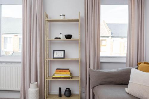 a living room with a book shelf next to a couch at Newly renovated large 4/5 bedroom Victorian terrace house with garden. in London