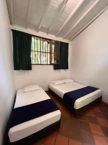 two twin beds in a room with a window at Yolo Hostel Medellin in Medellín
