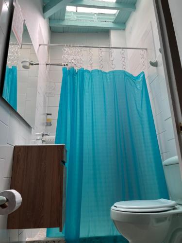 a bathroom with a blue shower curtain and a toilet at Yolo Hostel Medellin in Medellín