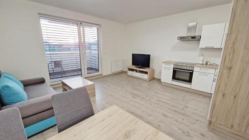 a living room with a couch and a tv and a kitchen at Apartmány Vinohrady in Trenčín