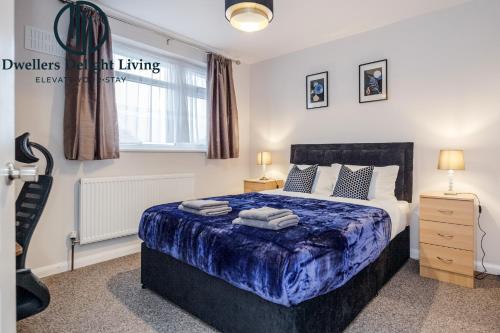 a bedroom with a large bed with a blue blanket at Dwellers Delight Living Ltd Serviced Accommodation Fabulous House 3 Bedroom, Hainault Prime Location ,Greater London with Parking & Wifi, 2 bathroom, Garden in Chigwell