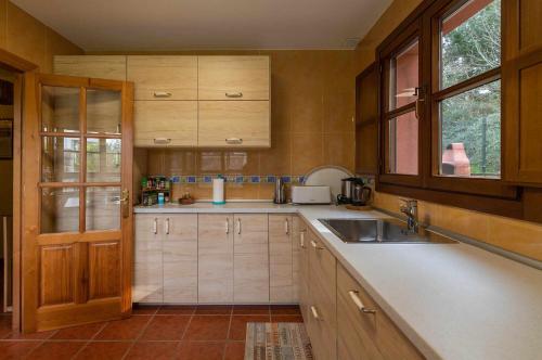 een keuken met houten kasten, een wastafel en een raam bij Vivienda Vacacional Casa Entrencinas in Collera