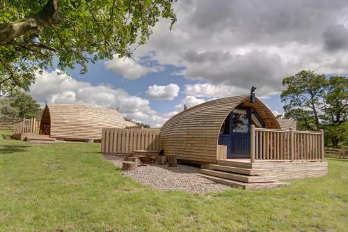 a couple of large wooden buildings in a field at Finest Retreats - Blackcleugh Glamping in Hexham