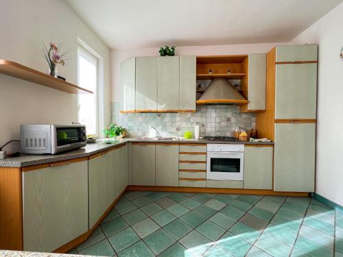 a kitchen with wooden cabinets and a microwave at Villetta a schiera con giardino - Val Trebbia 