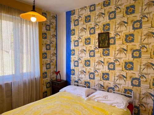 a bedroom with a bed and a wall covered in wallpaper at Villetta a schiera con giardino - Val Trebbia 