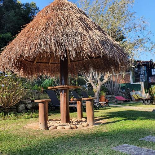 a hut with a table and stools in the grass at Pousada do Coura in Pouso Alto