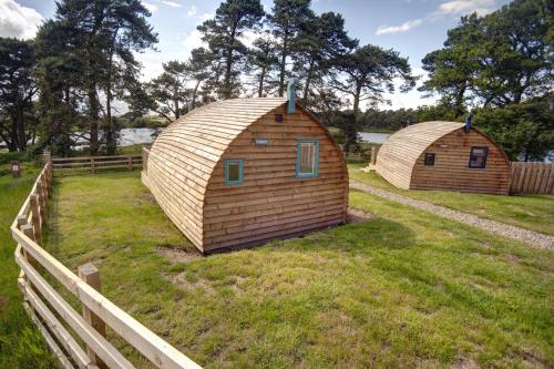 Deux cabanes en bois dans un champ à côté d'une clôture dans l'établissement Finest Retreats - The Wonneys Glamping, à Hexham